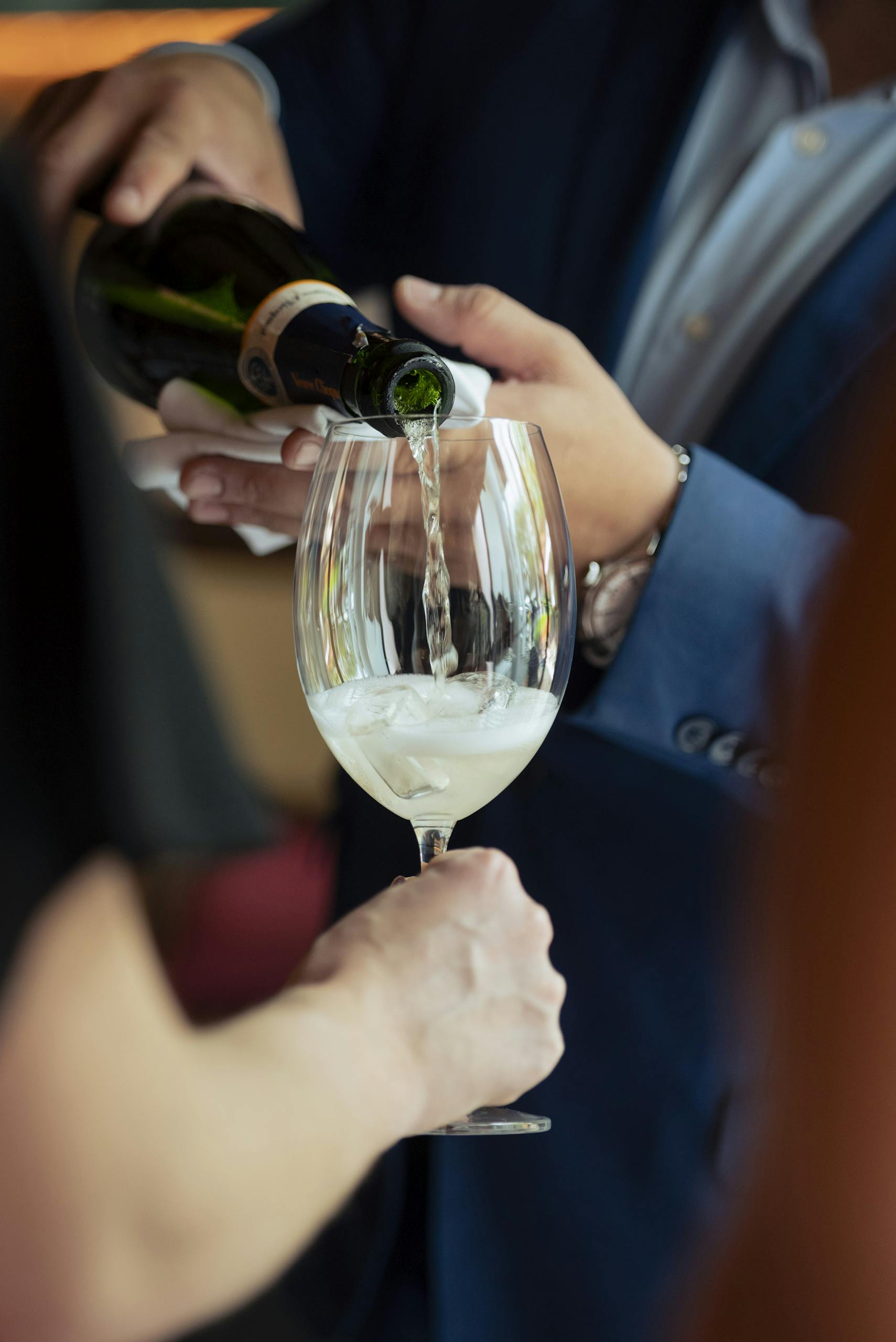A person in formal attire pouring champagne into a glass.