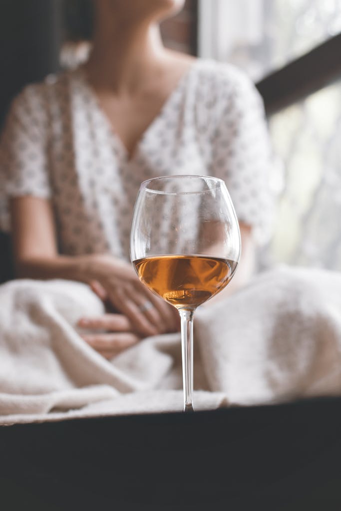 A woman sits by the window, enjoying a glass of wine. Cozy atmosphere.