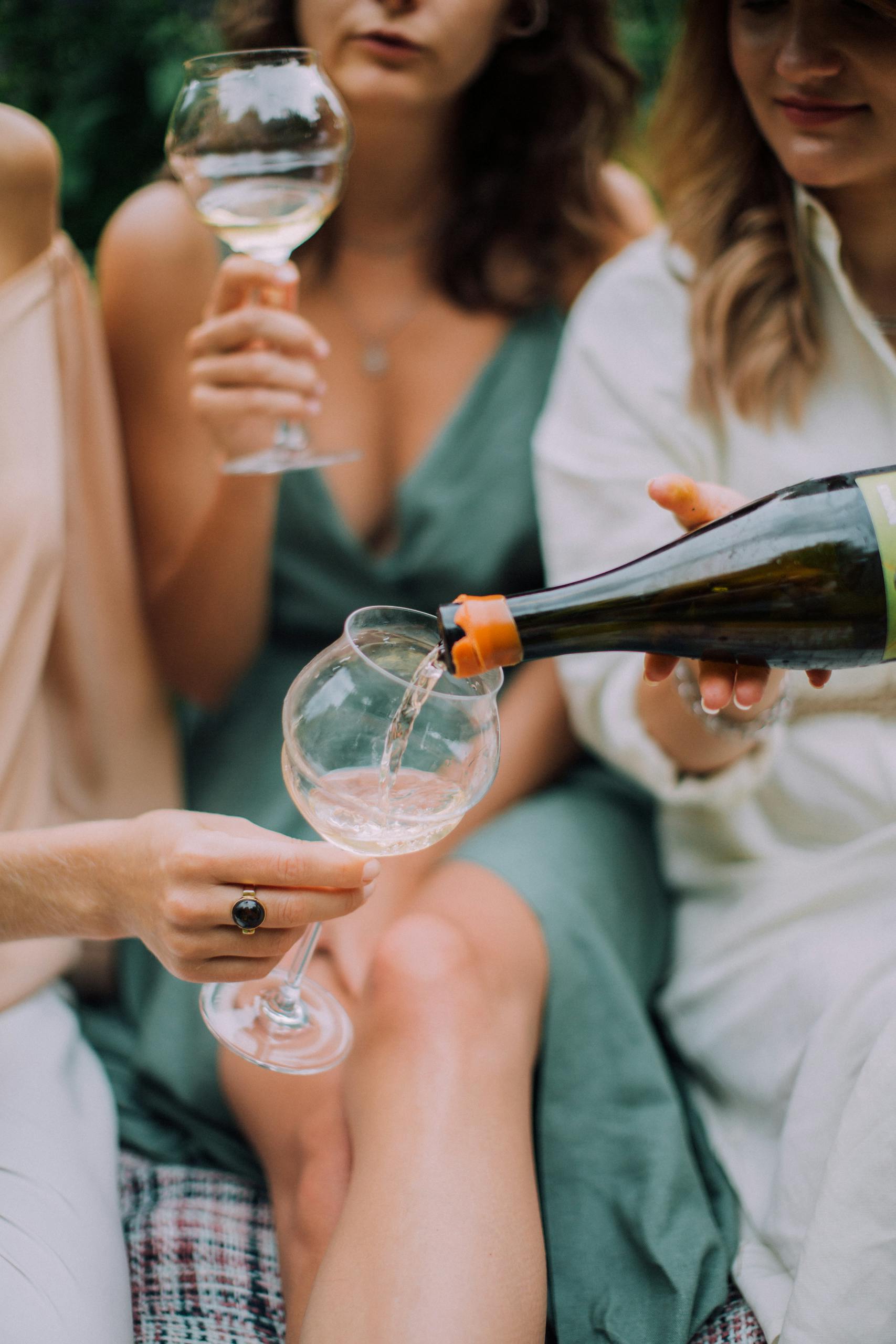 Casual gathering of women enjoying white wine outdoors, capturing a relaxed and joyful moment.